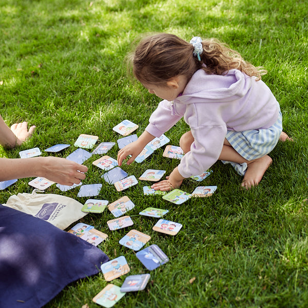 Zdjęcie przedstawia dziewczynkę grającą na trawie w "Memory o emocjach".