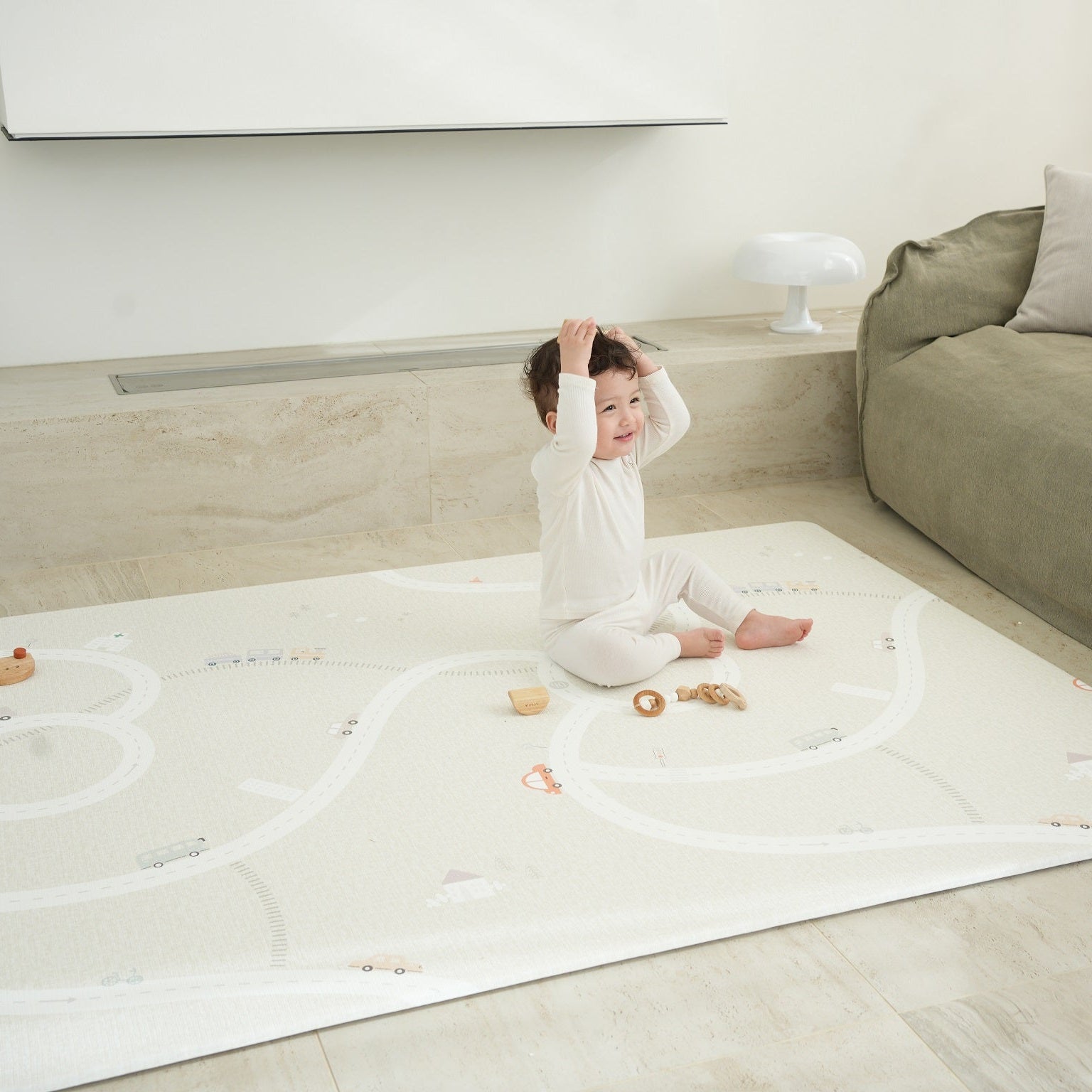 Dziecko siedzące na dwustronnej macie do zabawy marki Dwinguler w jasnym wnętrzu. Mata posiada delikatny wzór, zapewniając bezpieczną i komfortową przestrzeń do raczkowania i zabawy.