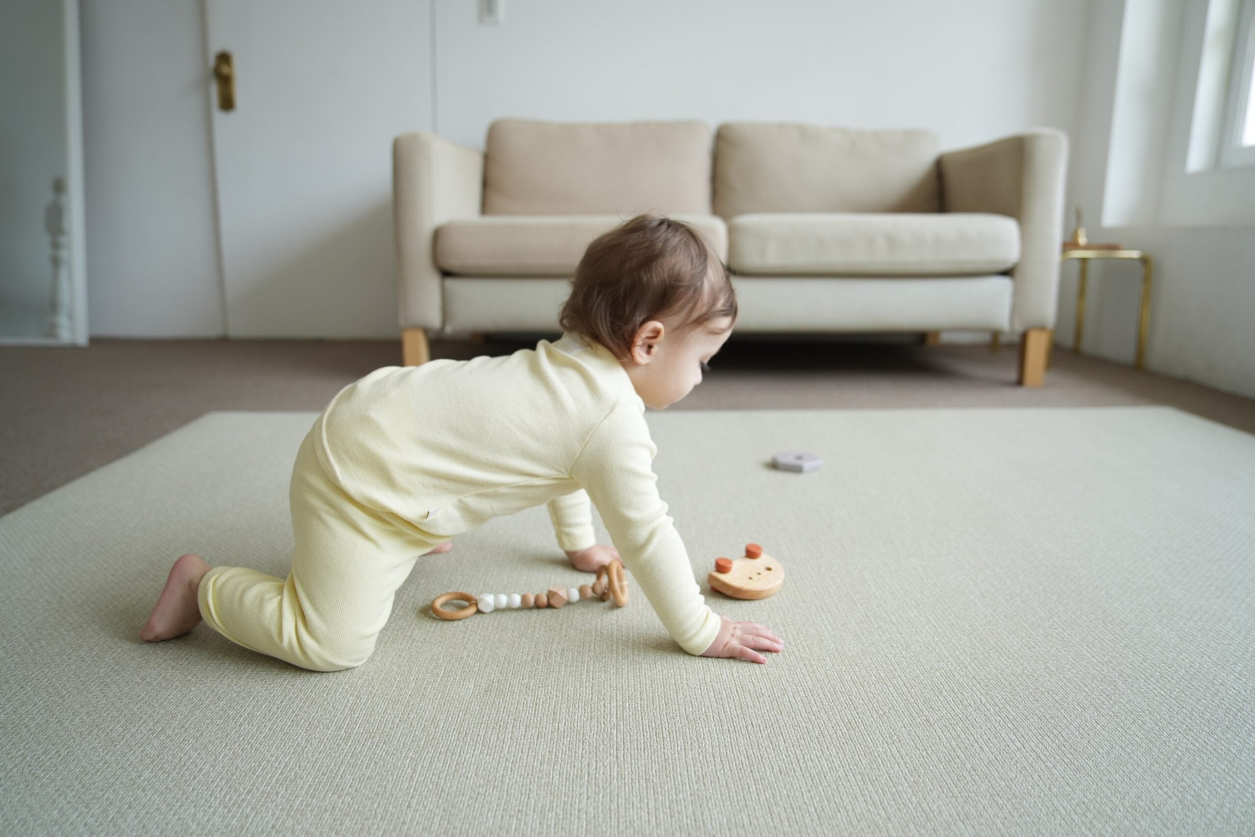 Dziecko siedzące na dwustronnej macie do zabawy marki Dwinguler w jasnym wnętrzu. Mata posiada delikatny wzór, zapewniając bezpieczną i komfortową przestrzeń do raczkowania i zabawy.