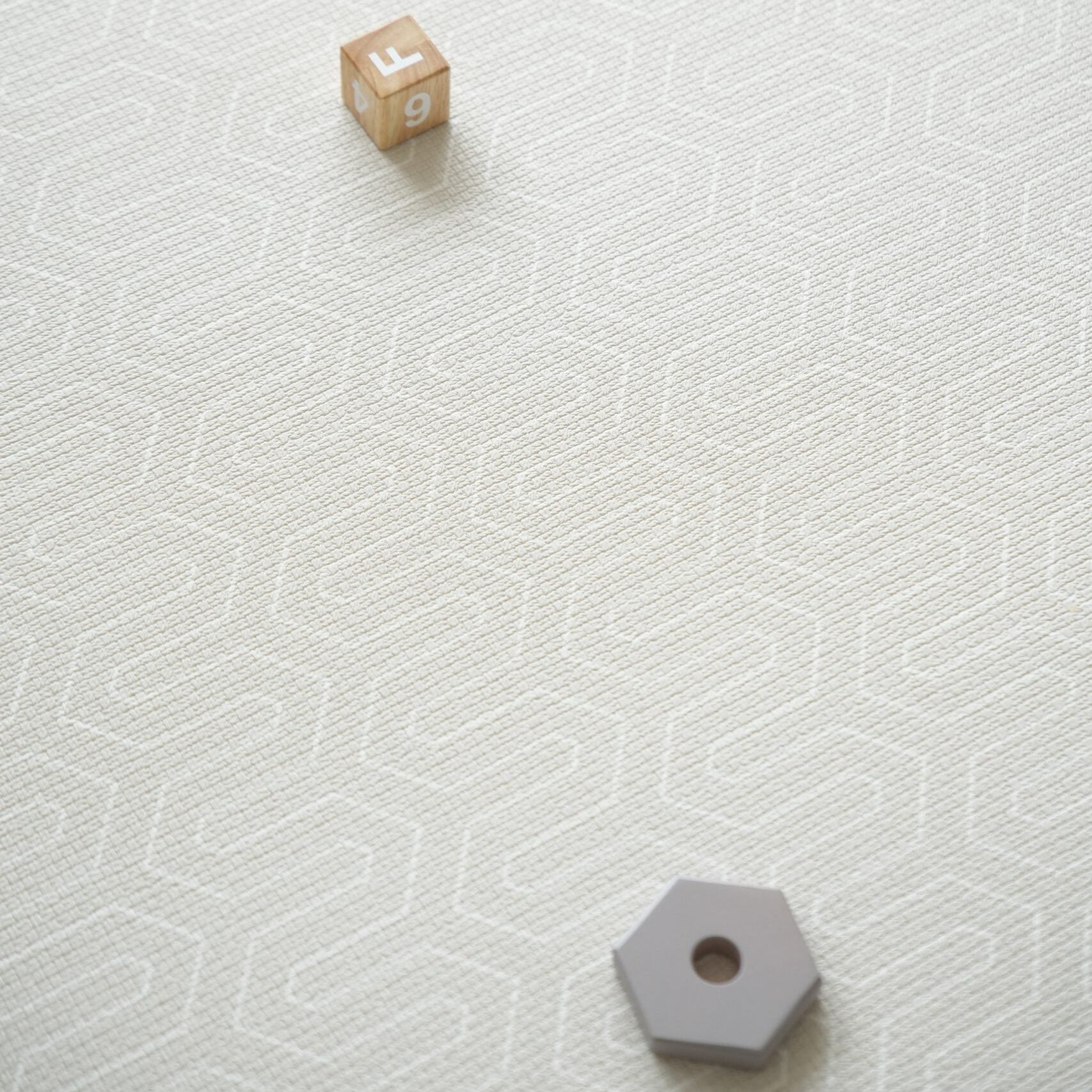 Dziecko siedzące na dwustronnej macie do zabawy marki Dwinguler w jasnym wnętrzu. Mata posiada delikatny wzór, zapewniając bezpieczną i komfortową przestrzeń do raczkowania i zabawy.