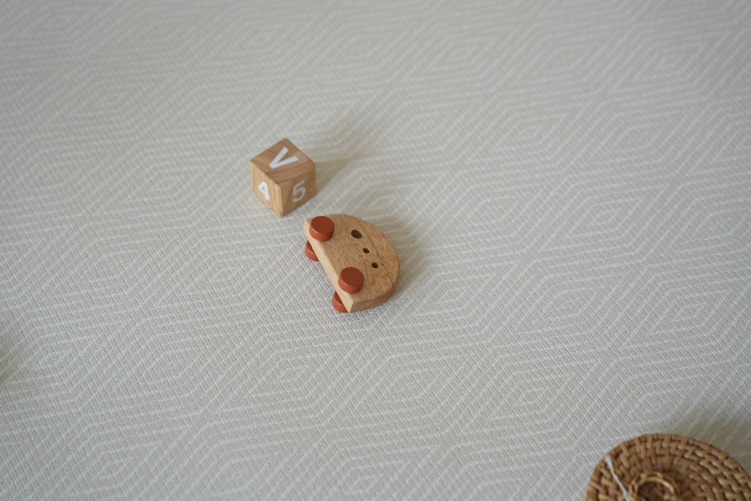 Dziecko siedzące na dwustronnej macie do zabawy marki Dwinguler w jasnym wnętrzu. Mata posiada delikatny wzór, zapewniając bezpieczną i komfortową przestrzeń do raczkowania i zabawy.