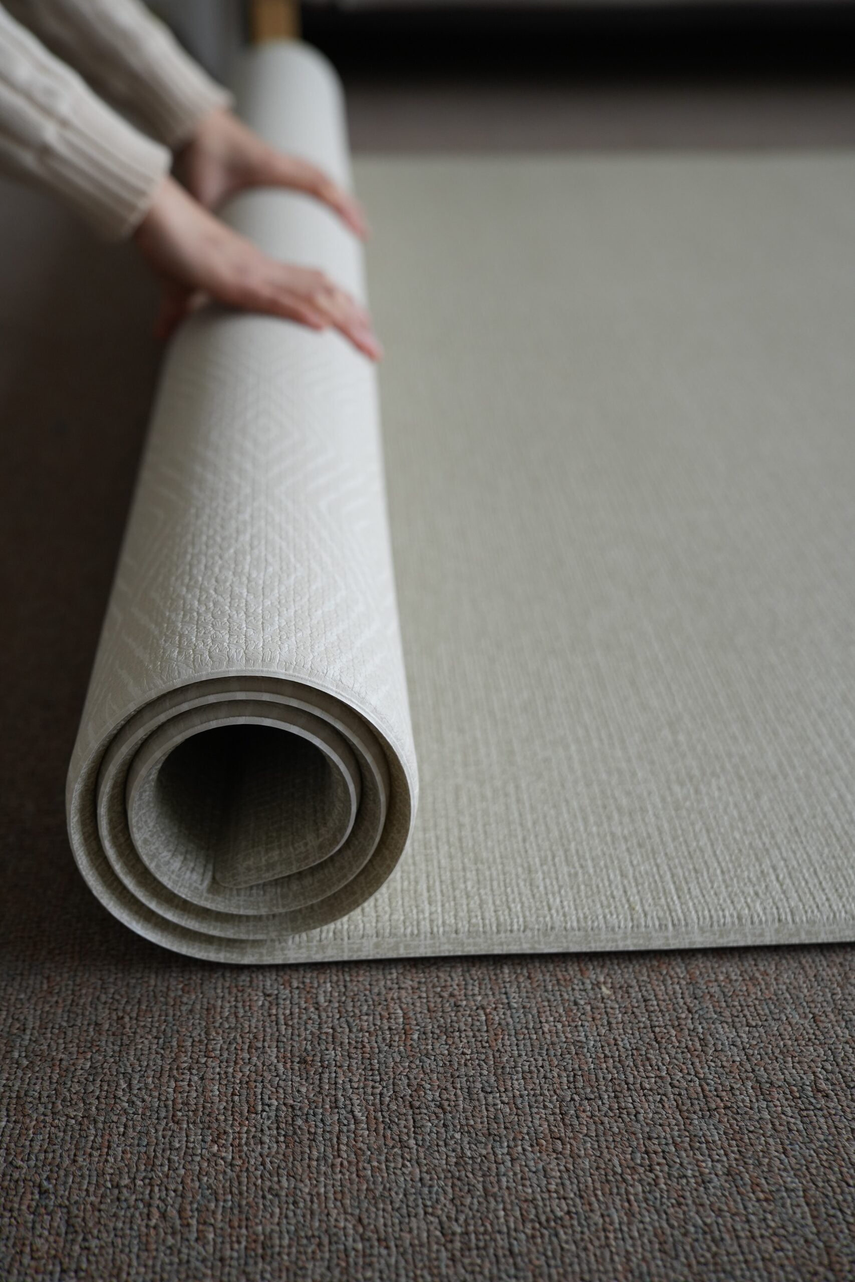 Dziecko siedzące na dwustronnej macie do zabawy marki Dwinguler w jasnym wnętrzu. Mata posiada delikatny wzór, zapewniając bezpieczną i komfortową przestrzeń do raczkowania i zabawy.