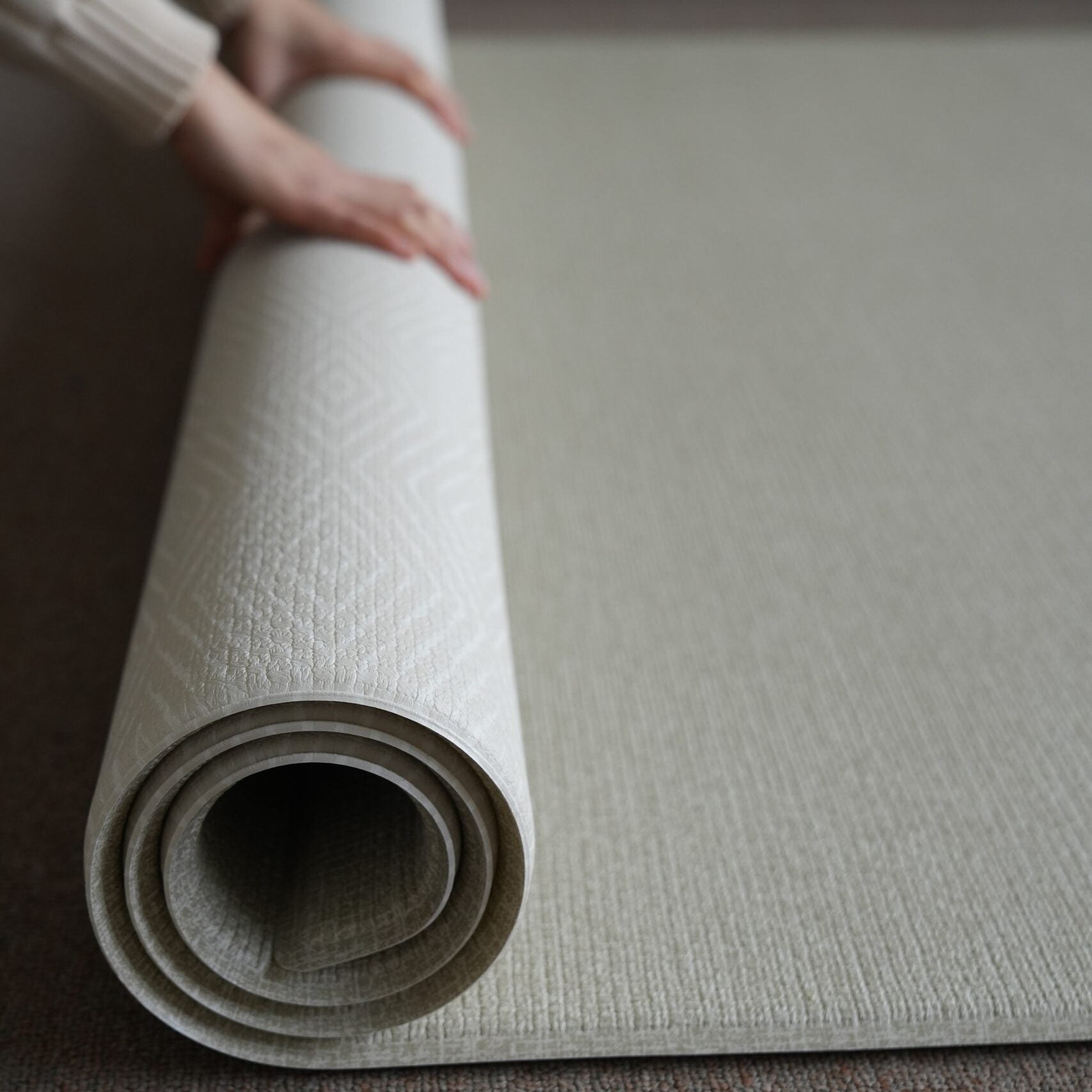 Dziecko siedzące na dwustronnej macie do zabawy marki Dwinguler w jasnym wnętrzu. Mata posiada delikatny wzór, zapewniając bezpieczną i komfortową przestrzeń do raczkowania i zabawy.