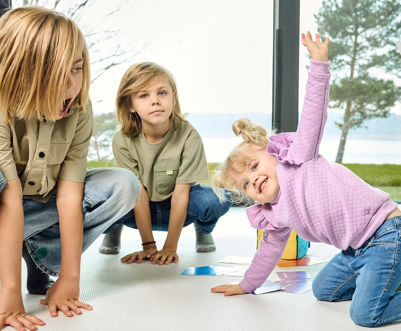 Na zdjęciu troje dzieci grających w grę "Kostka aktywności"