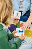 Na zdjęciu widoczne dłonie kobiety i dziecka; trzymają karty z zadaniami do gry "Kostka aktywności - mindfulness"