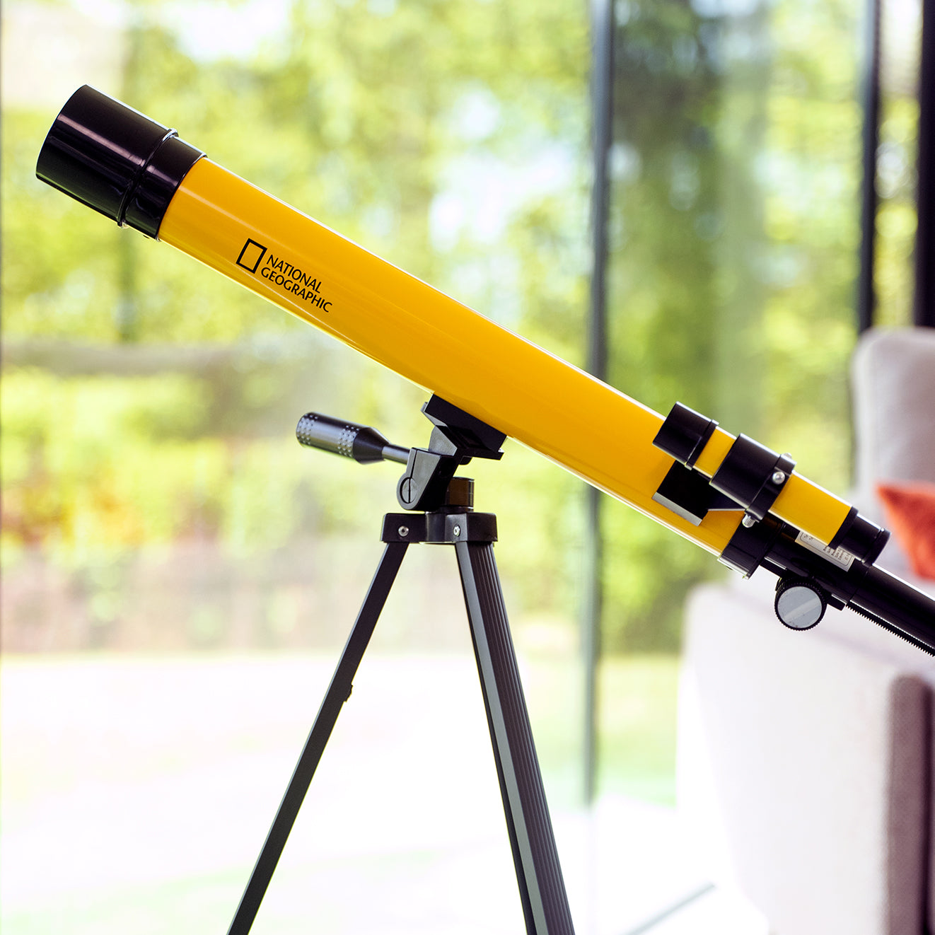 Teleskop Bresser 45/600 mm z rodziny National Geographic, w kolorze żółtym, umieszczony na statywie, przeznaczony do obserwacji astronomicznych, z lunetką celowniczą, różnymi okularami do zmiany powiększenia oraz możliwością użycia do obserwacji przyrody, idealny dla dzieci od 7 roku życia.