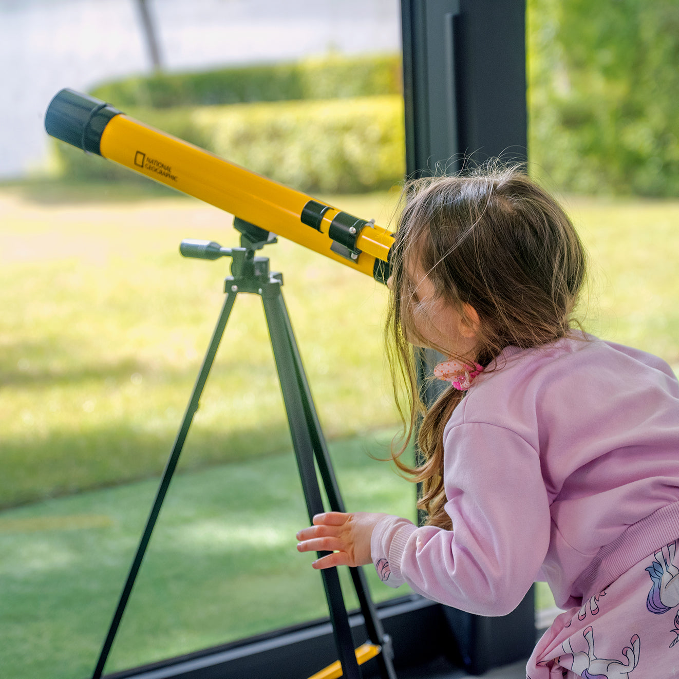 Teleskop Bresser 45/600 mm z rodziny National Geographic, w kolorze żółtym, umieszczony na statywie, przeznaczony do obserwacji astronomicznych, z lunetką celowniczą, różnymi okularami do zmiany powiększenia oraz możliwością użycia do obserwacji przyrody, idealny dla dzieci od 7 roku życia.