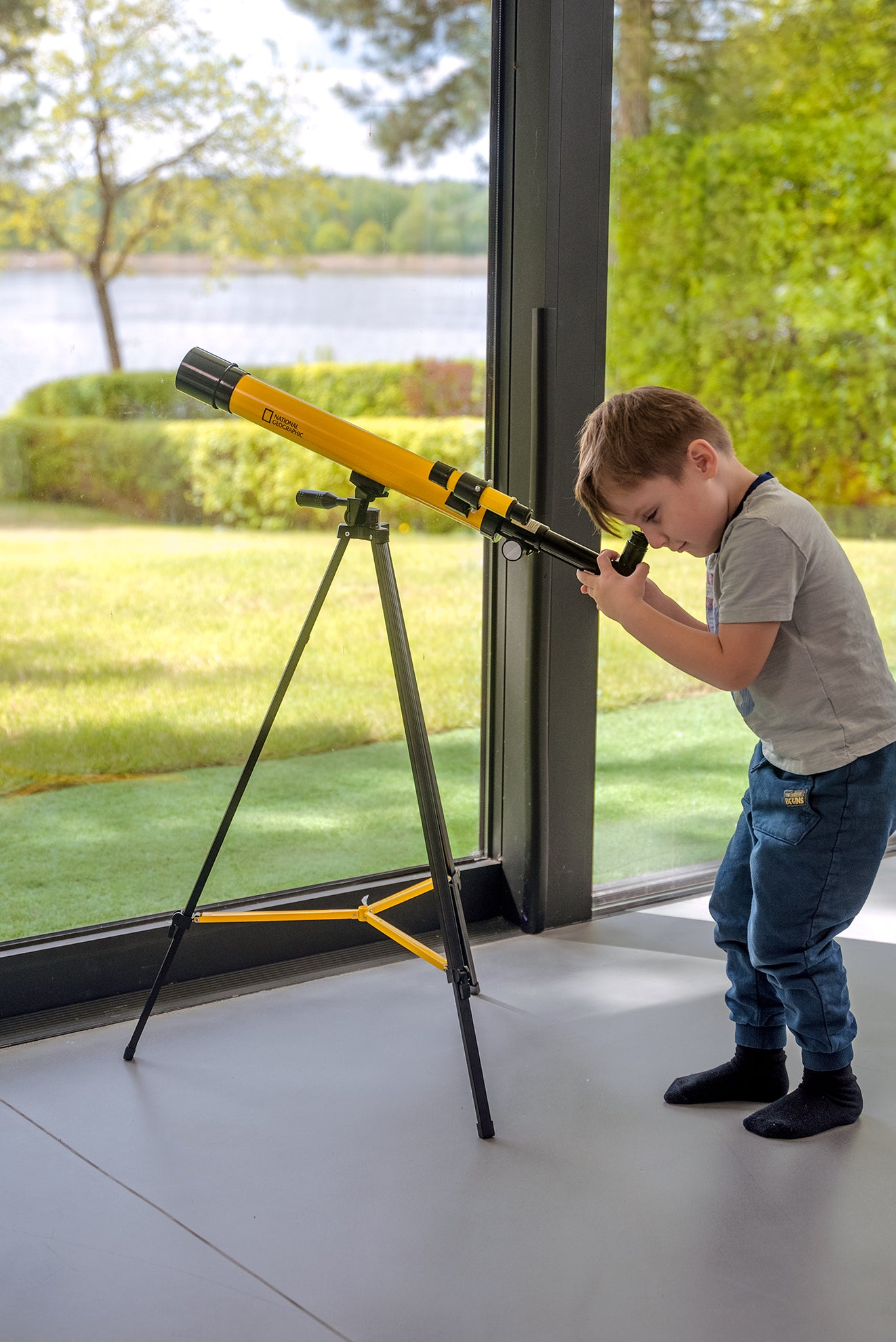 Teleskop Bresser 45/600 mm z rodziny National Geographic, w kolorze żółtym, umieszczony na statywie, przeznaczony do obserwacji astronomicznych, z lunetką celowniczą, różnymi okularami do zmiany powiększenia oraz możliwością użycia do obserwacji przyrody, idealny dla dzieci od 7 roku życia.