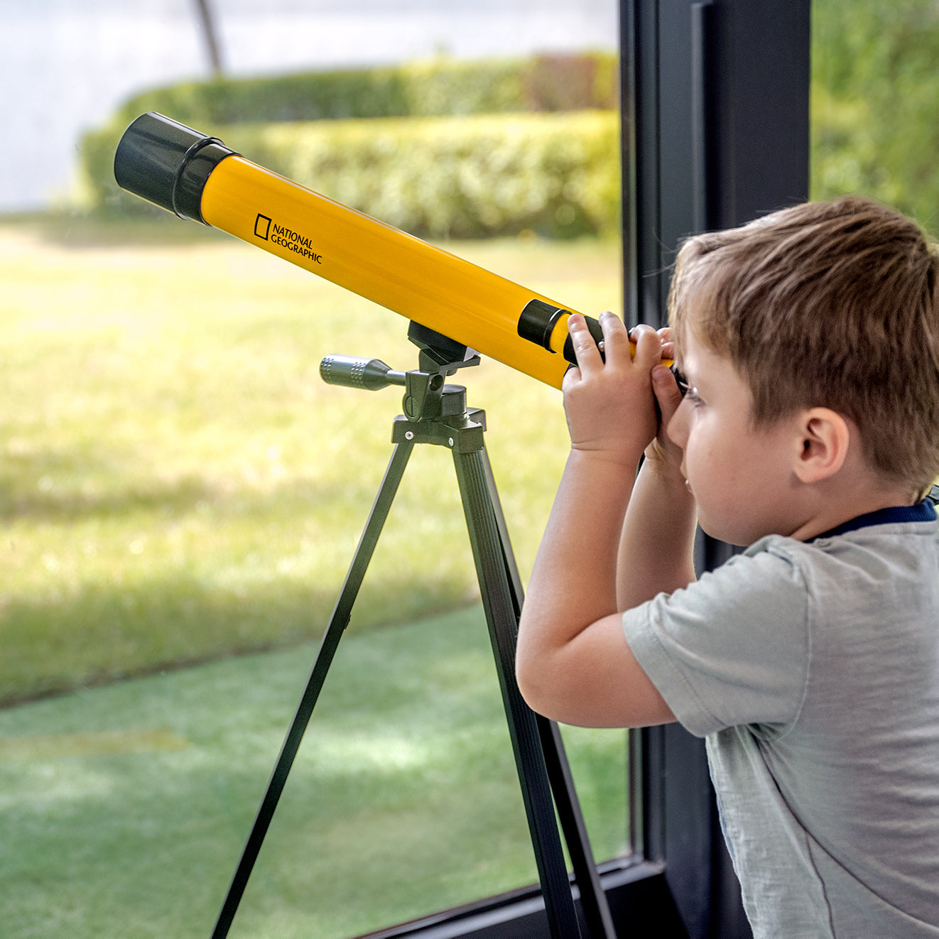 Teleskop Bresser 45/600 mm z rodziny National Geographic, w kolorze żółtym, umieszczony na statywie, przeznaczony do obserwacji astronomicznych, z lunetką celowniczą, różnymi okularami do zmiany powiększenia oraz możliwością użycia do obserwacji przyrody, idealny dla dzieci od 7 roku życia.