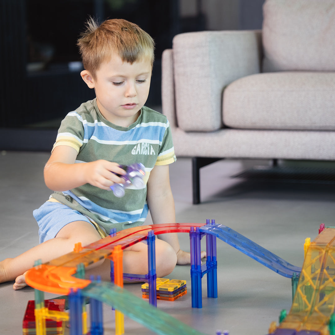 Klocki magnetyczne Cleverclixx Large Race Track Pastel składają się z 80 elementów, w tym dwóch samochodów (zielonego i fioletowego), 10 ramp, 12 płytek w kształcie łuku, 12 znaków drogowych, 10 płytek kwadratowych, 22 filarów oraz 12 płytek prostokątnych. Zestaw umożliwia budowanie różnorodnych torów wyścigowych i dodatkowych konstrukcji, co rozwija zdolności manualne, logiczne myślenie oraz kreatywność dzieci.