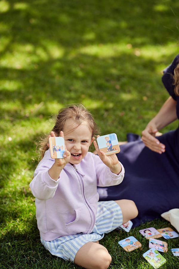 Zdjęcie przedstawia dziewczynkę pokazującą karty do gry "Memory o emocjach".