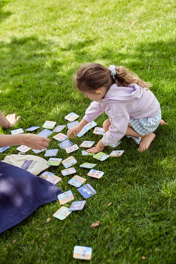 Zdjęcie przedstawia dziewczynkę grającą na trawie w "Memory o emocjach".