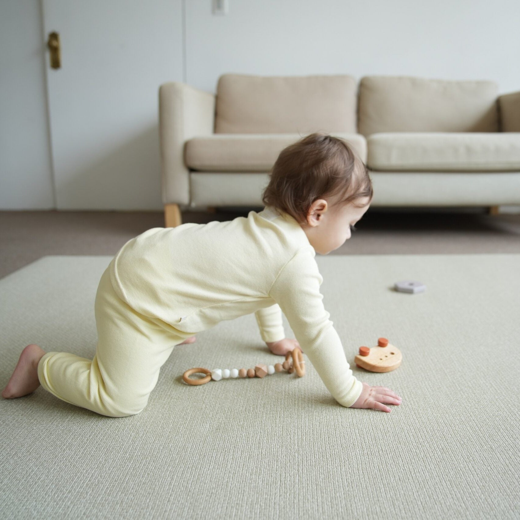 Dziecko siedzące na dwustronnej macie do zabawy marki Dwinguler w jasnym wnętrzu. Mata posiada delikatny wzór, zapewniając bezpieczną i komfortową przestrzeń do raczkowania i zabawy.