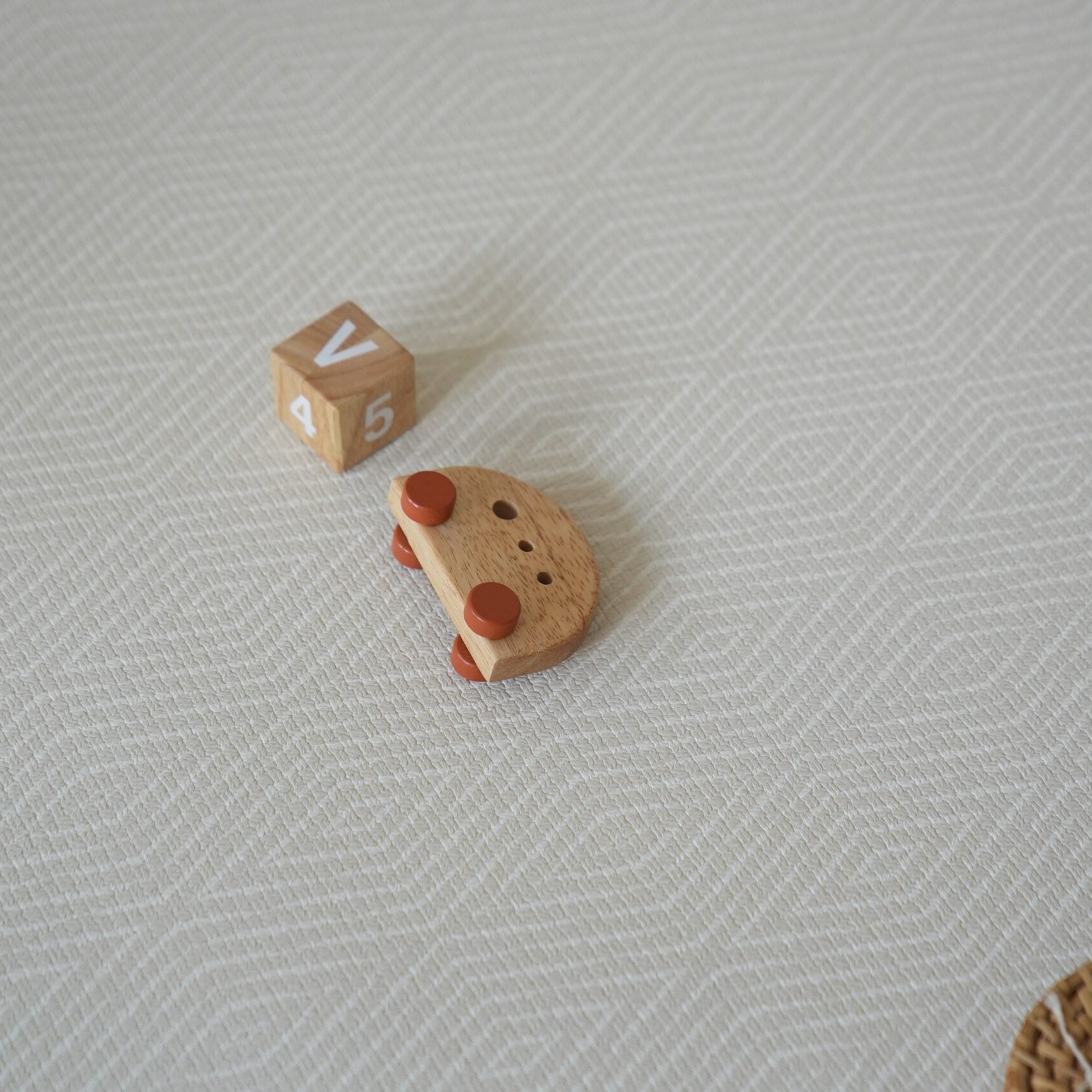 Dziecko siedzące na dwustronnej macie do zabawy marki Dwinguler w jasnym wnętrzu. Mata posiada delikatny wzór, zapewniając bezpieczną i komfortową przestrzeń do raczkowania i zabawy.