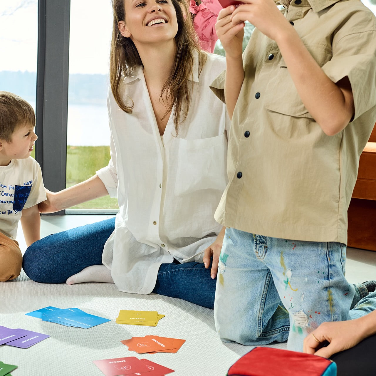 Na zdjęciu kobieta i troje dzieci grających w grę "Kostka aktywności". Chłopiec odczytuje zadanie z karty