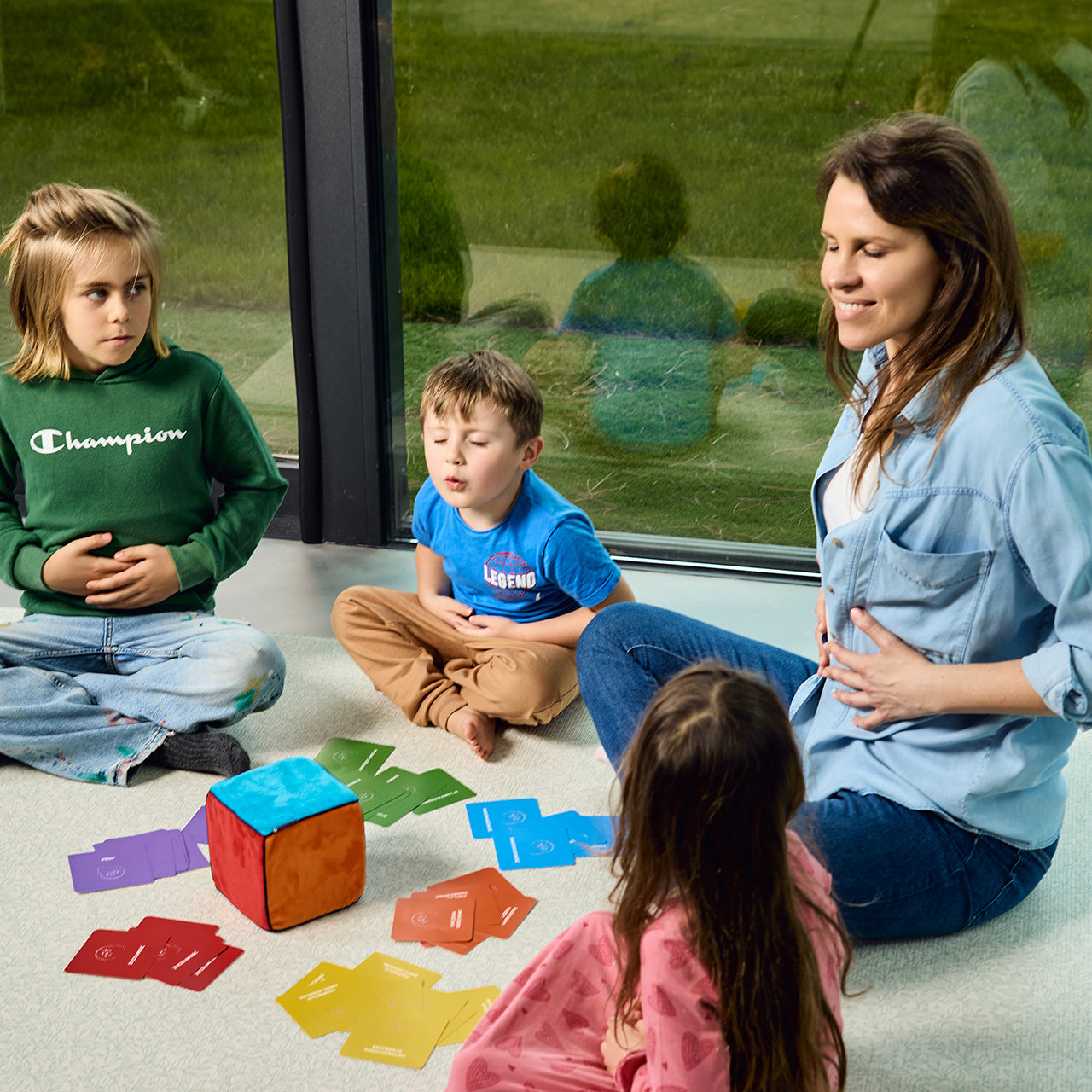 Na zdjęciu kobieta i troje dzieci grających w grę "Kostka aktywności - mindfulness"