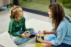 Na zdjęciu widoczne dziecko i kobieta, siedzący naprzeciwko siebie na podłodze i grający w grę "Kostka aktywności - mindfulness"