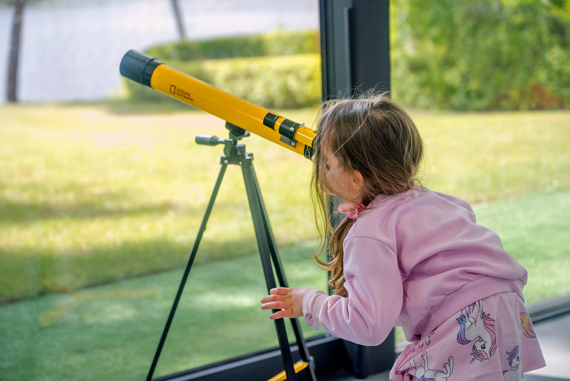 Teleskop Bresser 45/600 mm z rodziny National Geographic, w kolorze żółtym, umieszczony na statywie, przeznaczony do obserwacji astronomicznych, z lunetką celowniczą, różnymi okularami do zmiany powiększenia oraz możliwością użycia do obserwacji przyrody, idealny dla dzieci od 7 roku życia.