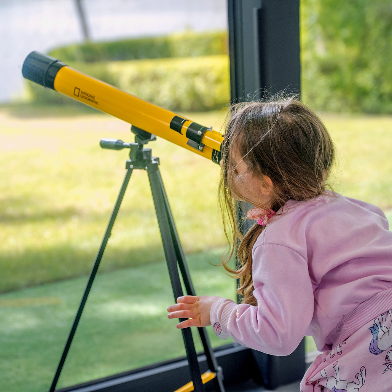 Teleskop Bresser 45/600 mm z rodziny National Geographic, w kolorze żółtym, umieszczony na statywie, przeznaczony do obserwacji astronomicznych, z lunetką celowniczą, różnymi okularami do zmiany powiększenia oraz możliwością użycia do obserwacji przyrody, idealny dla dzieci od 7 roku życia.