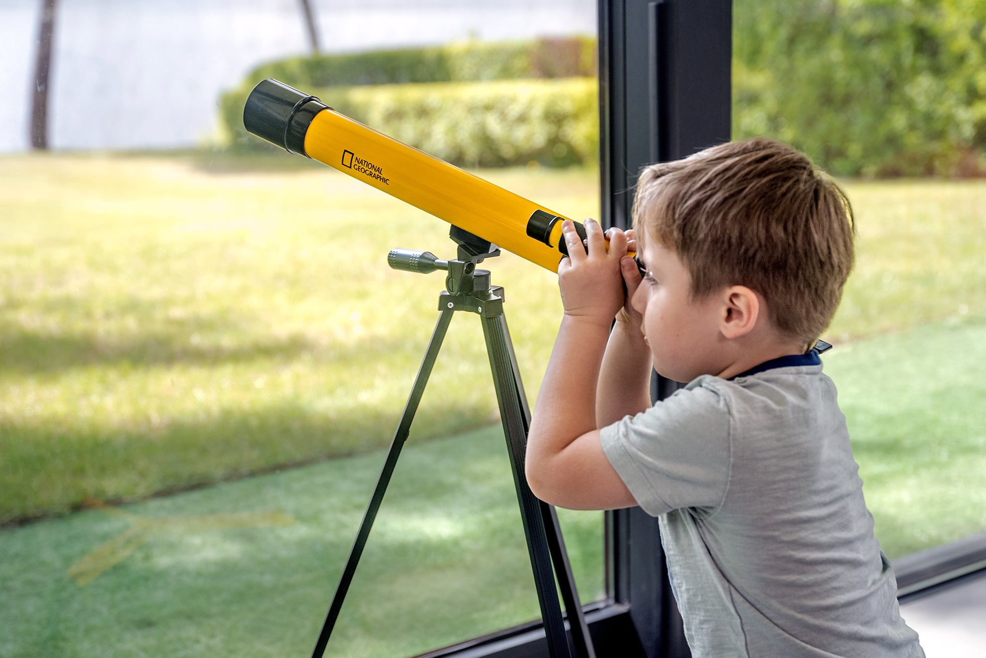 Teleskop Bresser 45/600 mm z rodziny National Geographic, w kolorze żółtym, umieszczony na statywie, przeznaczony do obserwacji astronomicznych, z lunetką celowniczą, różnymi okularami do zmiany powiększenia oraz możliwością użycia do obserwacji przyrody, idealny dla dzieci od 7 roku życia.