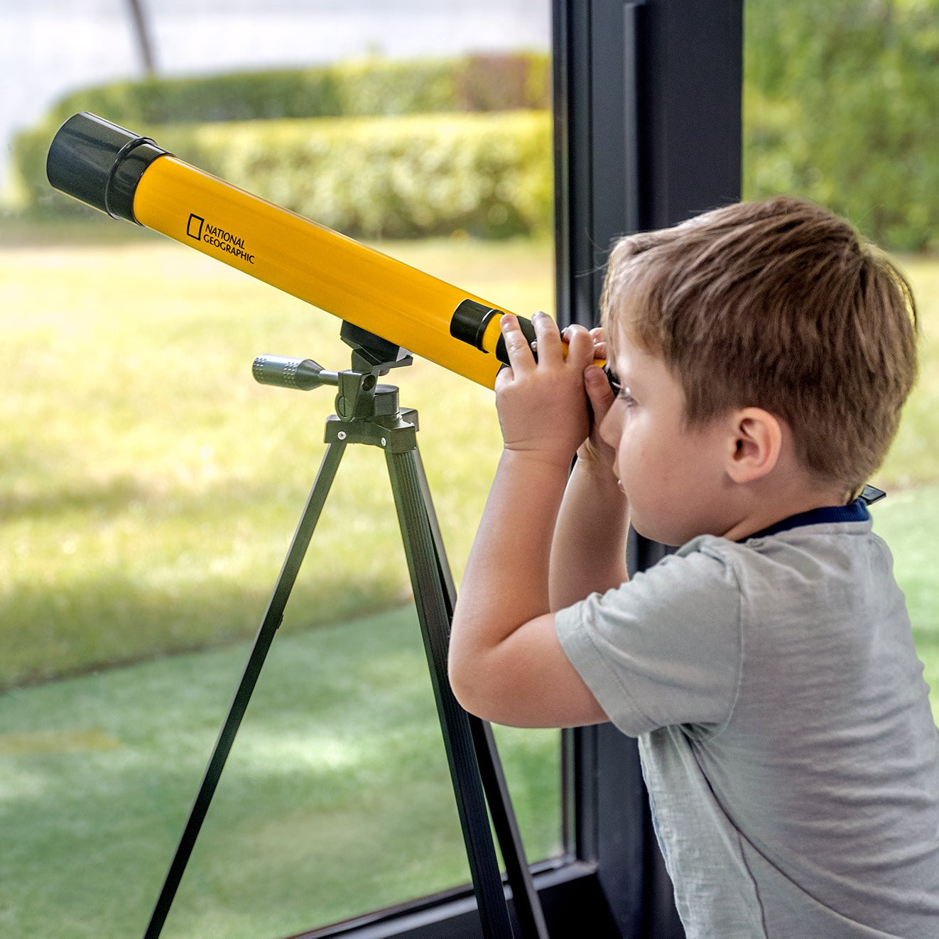 Teleskop Bresser 45/600 mm z rodziny National Geographic, w kolorze żółtym, umieszczony na statywie, przeznaczony do obserwacji astronomicznych, z lunetką celowniczą, różnymi okularami do zmiany powiększenia oraz możliwością użycia do obserwacji przyrody, idealny dla dzieci od 7 roku życia.