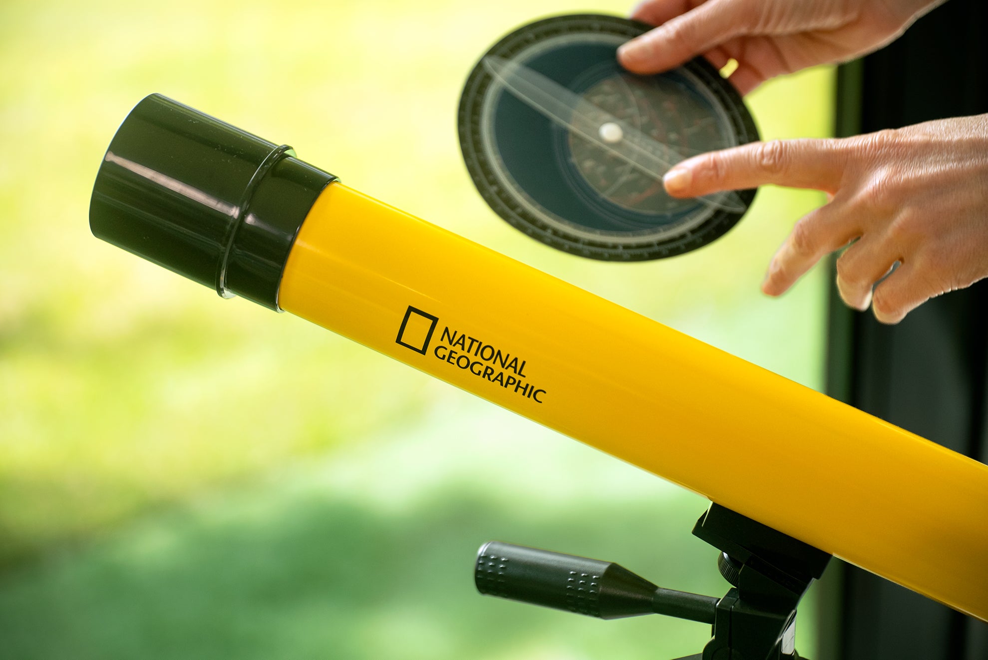 Teleskop Bresser 45/600 mm z rodziny National Geographic, w kolorze żółtym, umieszczony na statywie, przeznaczony do obserwacji astronomicznych, z lunetką celowniczą, różnymi okularami do zmiany powiększenia oraz możliwością użycia do obserwacji przyrody, idealny dla dzieci od 7 roku życia.