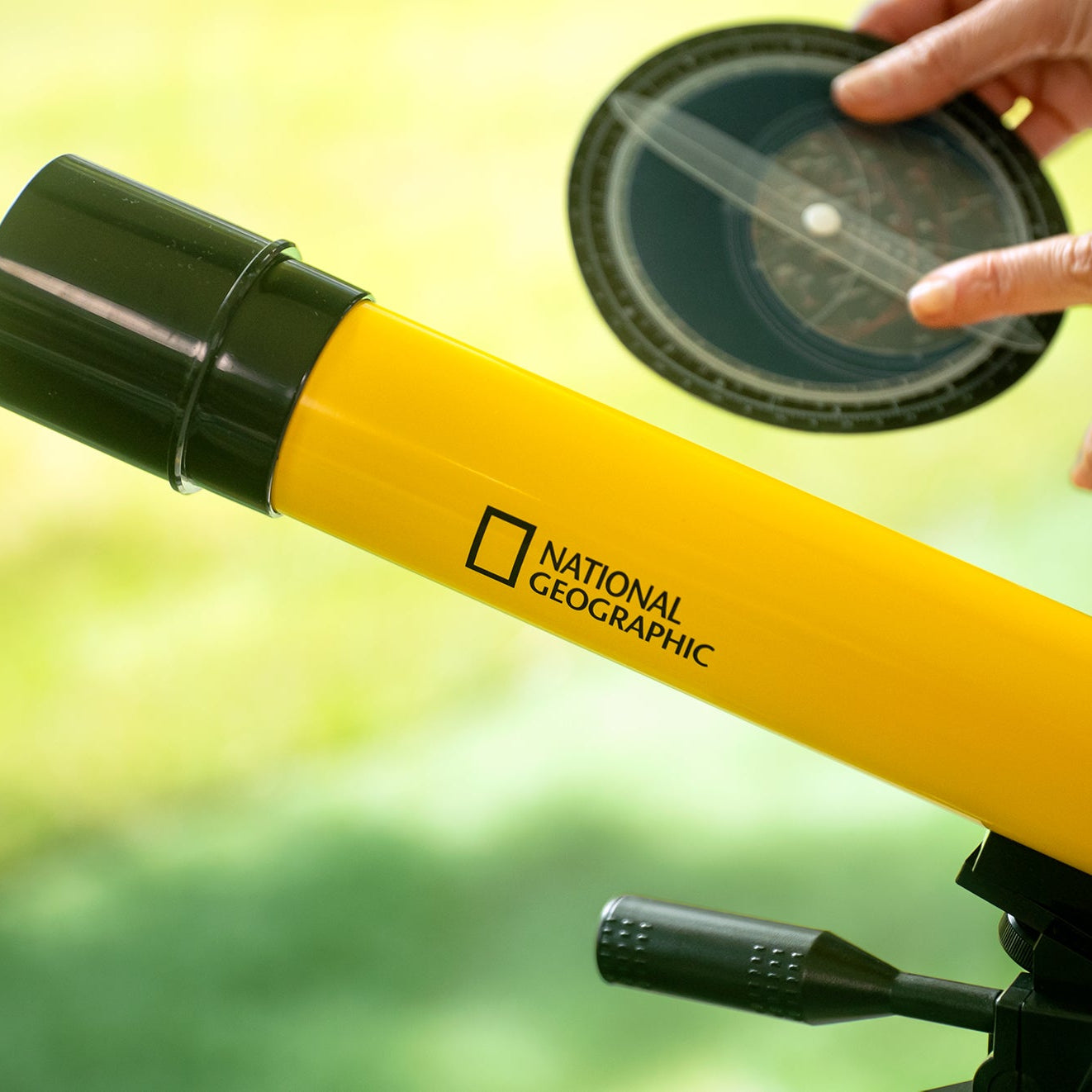 Teleskop Bresser 45/600 mm z rodziny National Geographic, w kolorze żółtym, umieszczony na statywie, przeznaczony do obserwacji astronomicznych, z lunetką celowniczą, różnymi okularami do zmiany powiększenia oraz możliwością użycia do obserwacji przyrody, idealny dla dzieci od 7 roku życia.