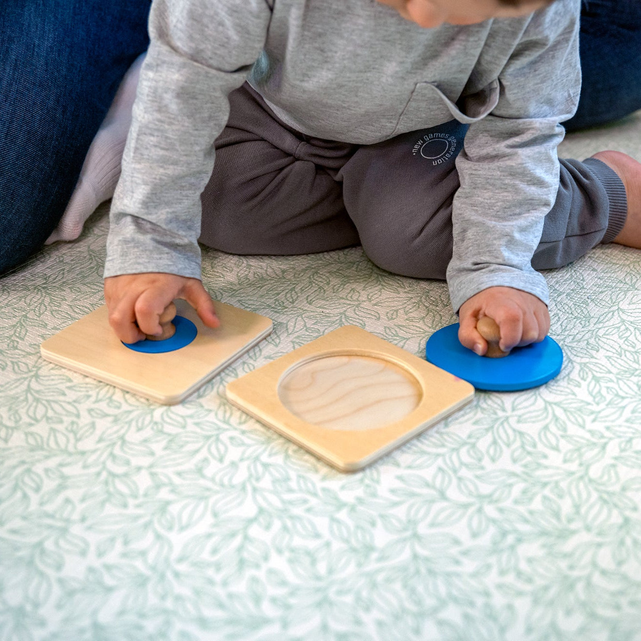 Motoryka mała dziecka przy puzzlach geometrycznych Montessori – zbliżenie na rączki dopasowujące kształty do otworów