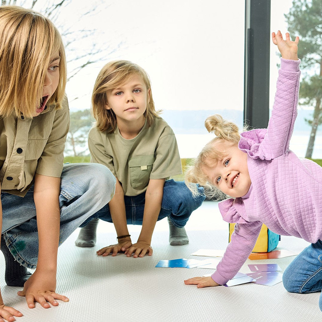 Troje dzieci grających w grę "Kostka aktywności"